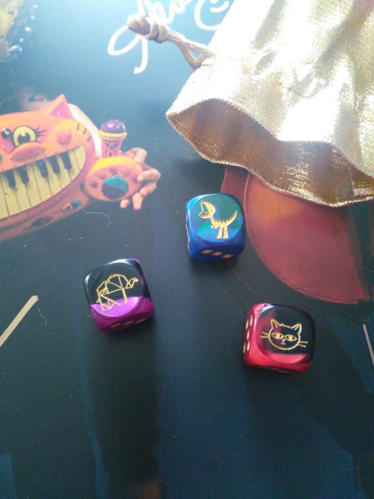 Doubleclicks D6 dice, featuring a dinosaur, a cat, and a tiny paper elephant.