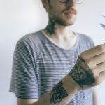 nerdy tattooed man holding plant